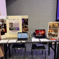 Samara Russell and Cora Van Houwelingen stand next to their poster and share a table.